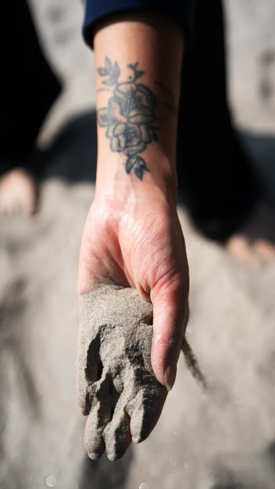 Detalle de la mano de Katherine Velasquez con arena en la playa